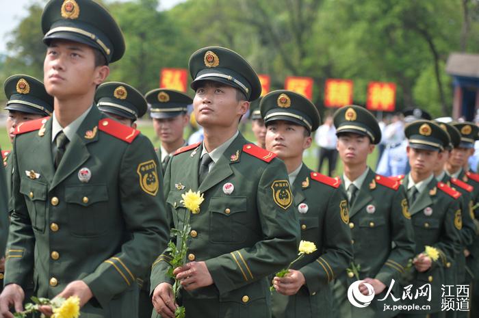  武警战士手持鲜花，仰望红军烈士纪念塔。
