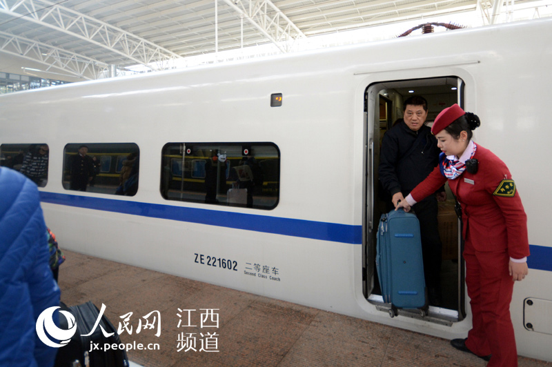 动车进站了，彭茗在车门口协助旅客下车。
