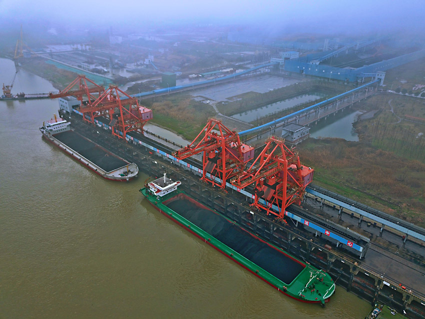 2月14日，兩艘來自江蘇太倉的運煤船停靠在江西煤炭儲備中心九江港口，卸船機抓斗正在向傳送帶上轉運煤炭。（無人機拍攝）