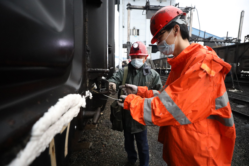 2月14日，在江西省煤炭儲備中心鐵路專用線內，九江車務段琵琶湖站貨運員正在檢查運煤專列的車門鎖閉加固情況。（丁波 攝）