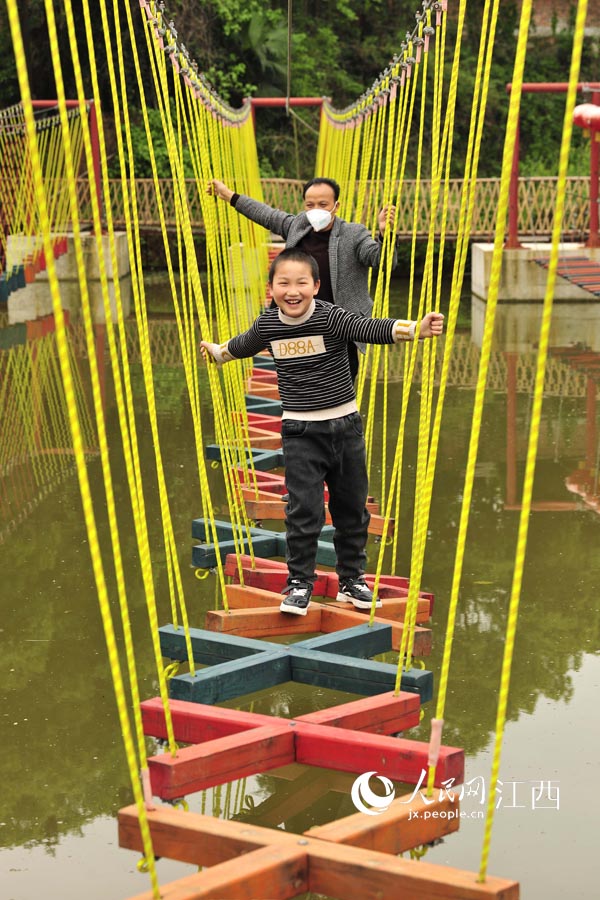 在萬載縣鵝峰鄉涂泉村一農庄，游客在“水上獨木吊架”上游玩。（鄧龍華/攝）