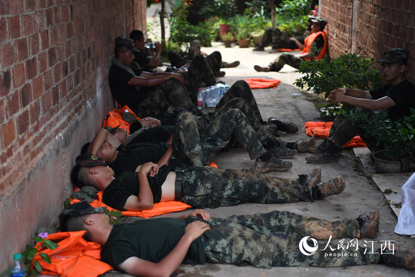13日中午时分，烈日当头，轮休的武警战士在大堤不远处民房的走廊内席地而卧，他们的睡姿令人心疼。（人民网 时雨/摄）