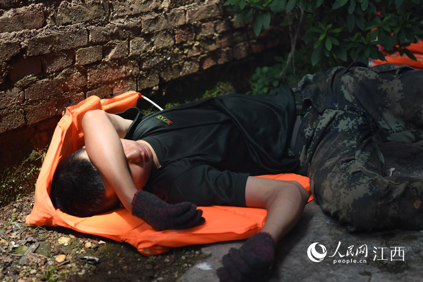 13日中午時分，烈日當頭，輪休的武警戰士在大堤不遠處民房的走廊內席地而臥，他們的睡姿令人心疼。（人民網 時雨/攝）