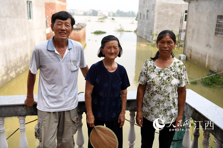 张瑶康（左）和他83岁的母亲（中）以及妻子（右）留守在被洪水围困的家中。（人民网 时雨/摄）