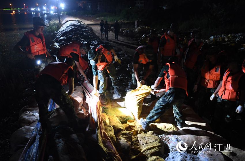 17日深夜，武警江西总队机动支队的官兵们正在对加高的沙袋进行加固。（人民网 时雨/摄）