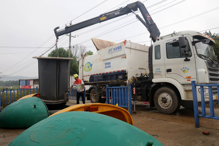 吊裝式垃圾車正在把垃圾池裡的垃圾整桶吊裝裝車轉運。