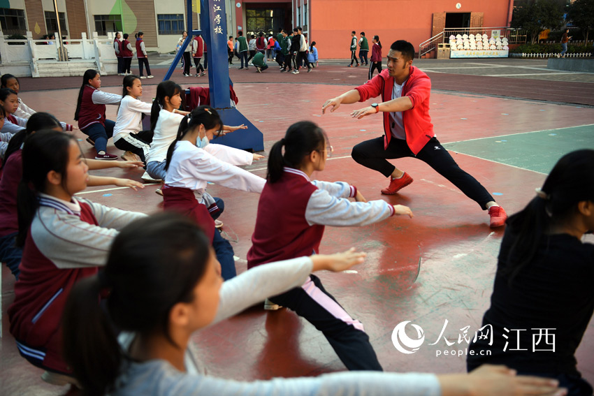 李向陽在操場上帶領孩子們做熱身運動。（人民網 時雨/攝）