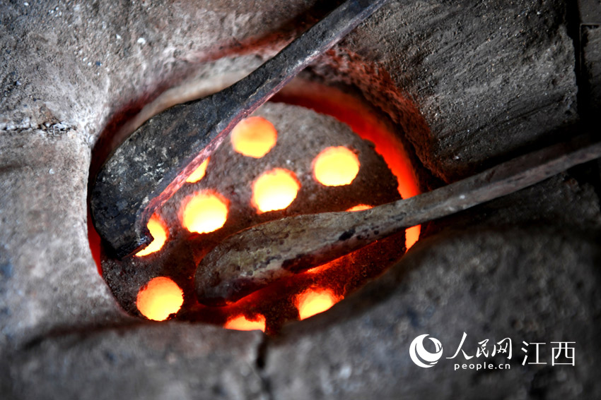 劉建強將焊棒放在蜂窩煤上烤，等到燒紅時就可以焊接制作錫器。（人民網 時雨 攝）