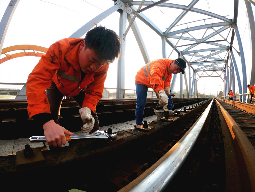 橋梁工對山下渡大橋鋼軌螺栓進行復擰。黃鐘濱 攝