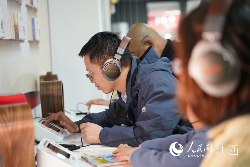 在“有聲圖書館”內，市民通過手機掃描二維碼在線免費“聽書”。（李強 攝）
