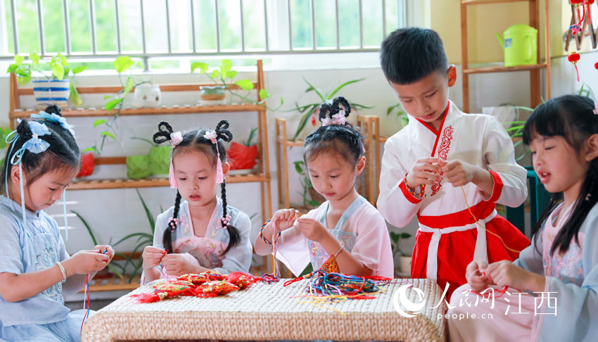 吉安市吉州區古南鎮街道水岸綠洲幼兒園小朋友正在編織五彩繩。（李軍 攝）
