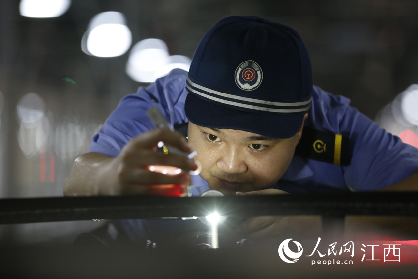 南昌西動車二所工長劉鵬正在測量動車組受電弓高度。（丁波 攝）