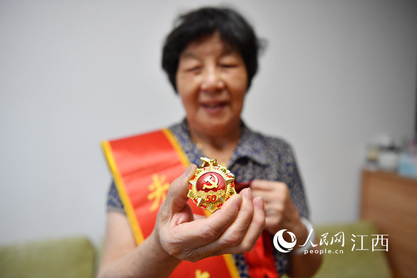 81歲的陶桂蓮在鏡頭前展示“光榮在黨50年”獎章。（人民網 時雨攝）