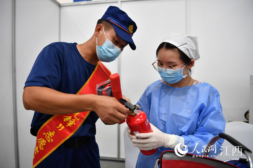 志願服務隊成員向接種醫生派發慰問品，並教授她們正確使用滅火器材。（人民網 時雨攝）