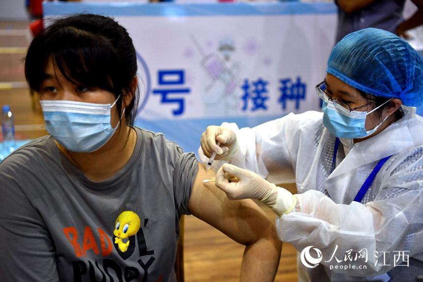 在江西省体育馆的新冠疫苗方舱接种点内,高中生正在接种新冠疫苗。(人民网 时雨摄)