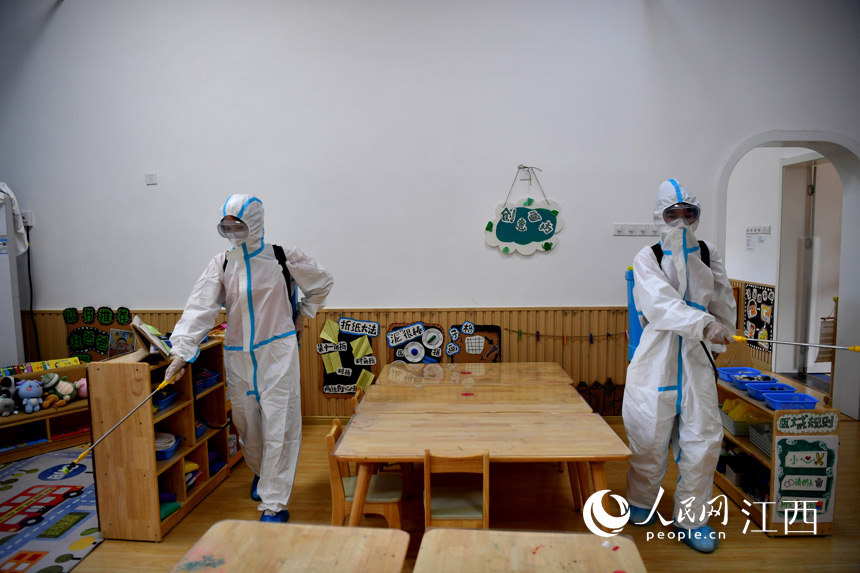 身穿防護服的員工正在對校園進行消殺。（人民網 時雨攝）