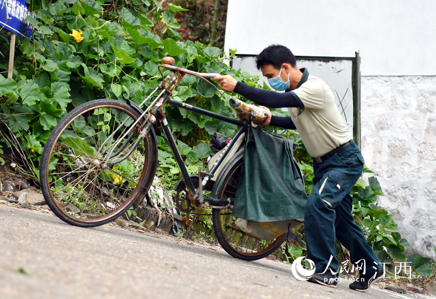 遇到上坡路，鄧六林艱難推行自行車。（人民網 時雨攝）