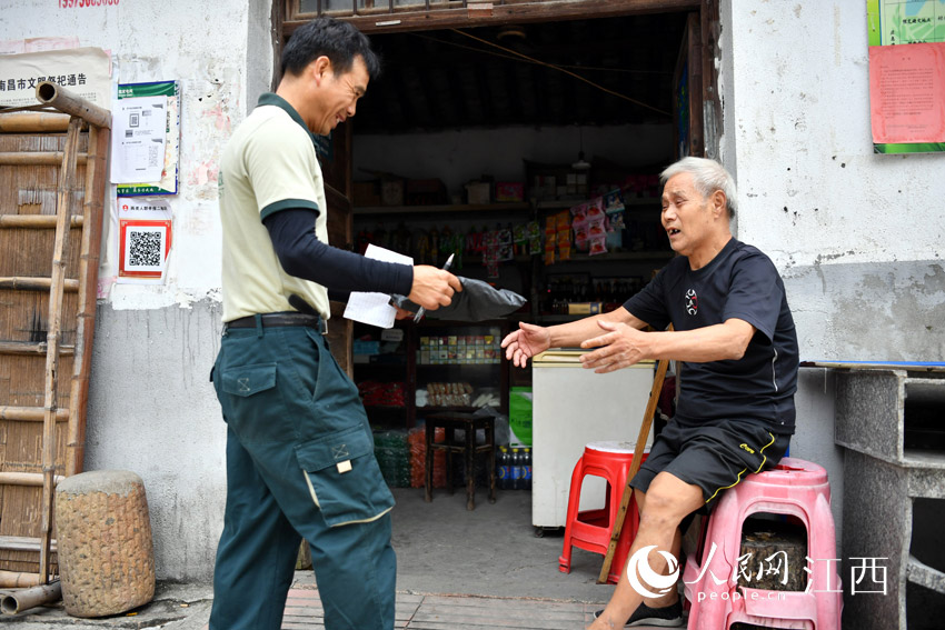 鄧六林為一位村民送上包裹。23年來，他與村民們結下了深厚的友誼。（人民網 時雨攝）