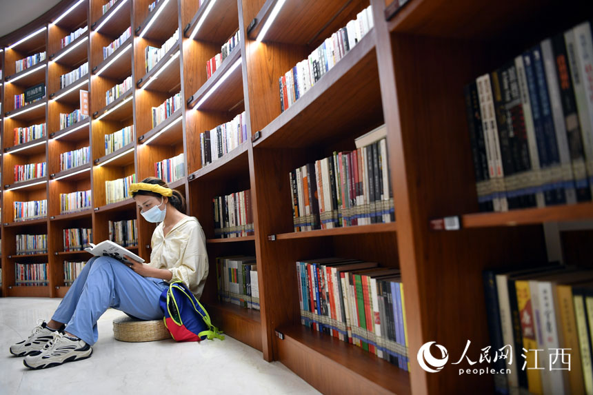 一位市民正依靠書架認真讀書。人民網 時雨攝