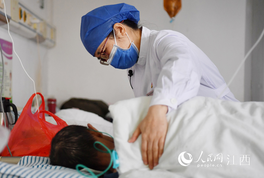 在病房裡，胡敏華正在輕拍一名艾滋病患者的背部，安撫患者的情緒。 人民網 時雨攝