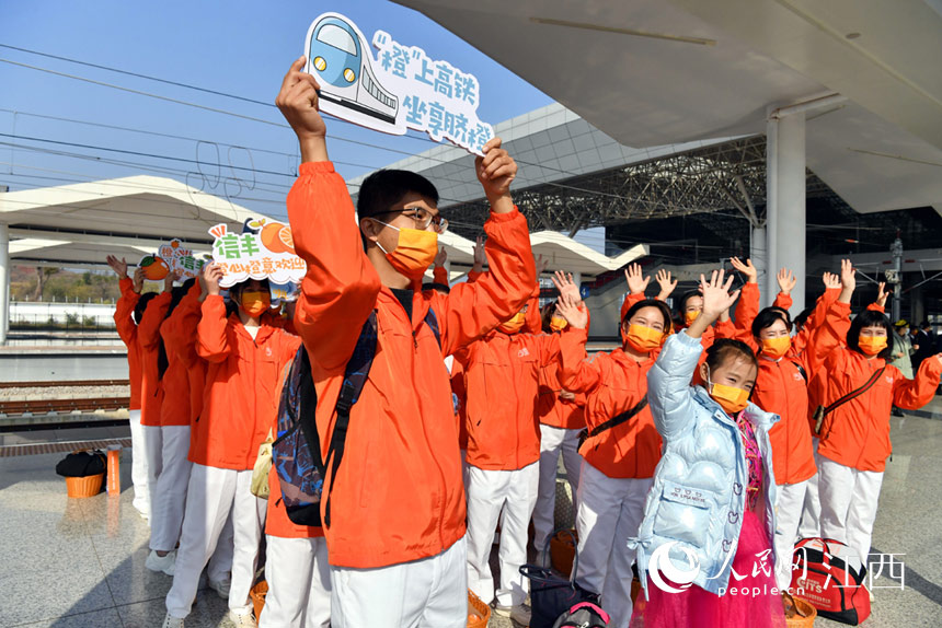 志願者在高鐵站台迎接“世界橙鄉 贛州信豐”號高鐵進站。 人民網 時雨攝