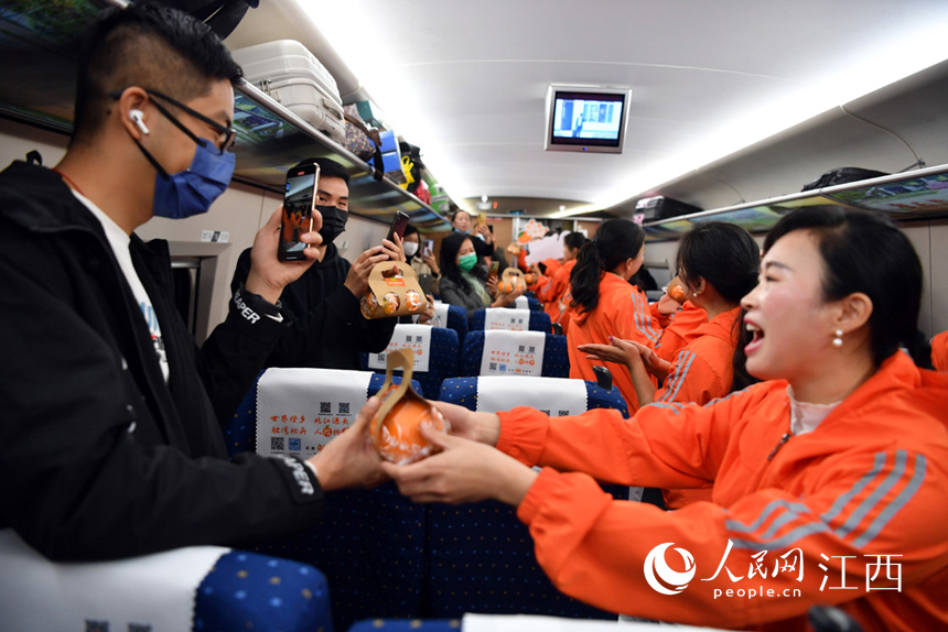 志願者為乘客送上信豐臍橙。 人民網 時雨攝