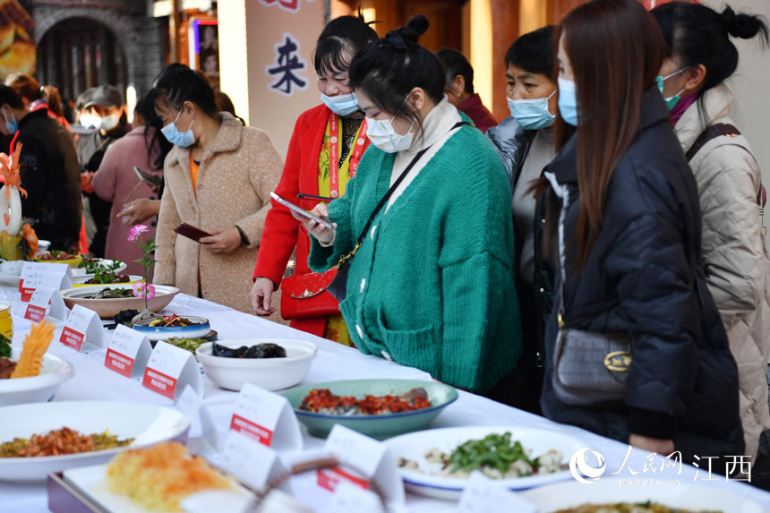 市民和游客正在萍鄉市南正街觀賞一道道贛菜美食。 人民網 時雨攝