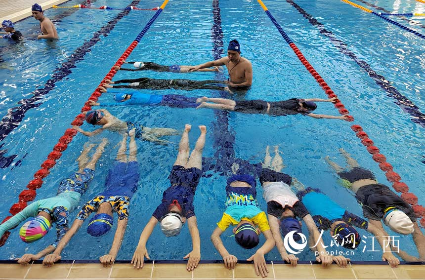 學校的游泳館裡，孩子們在教練指導下練習游泳技能。 人民網 時雨攝