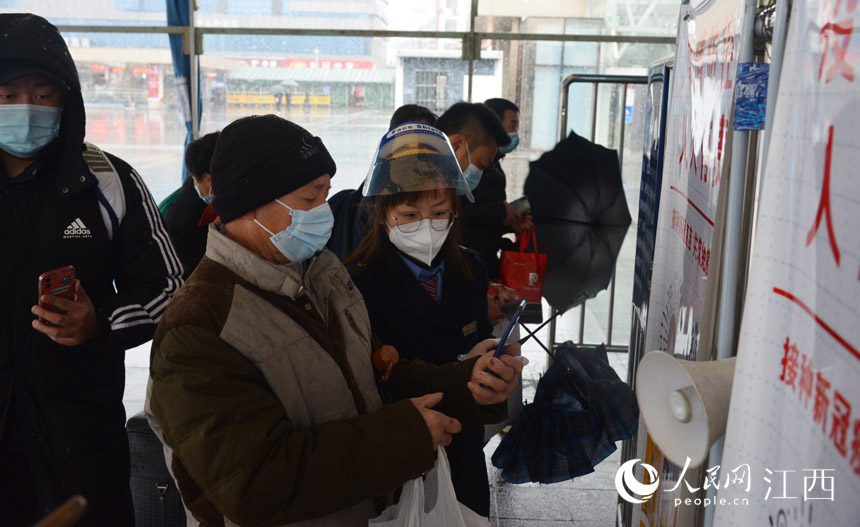 九江車務段工作人員在進站口協助旅客掃防疫行程碼，方便旅客快速進站。楊銳 攝