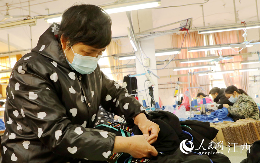 在永新縣禾川鎮一家服飾企業生產車間裡，工人正在趕制訂單。劉平華攝