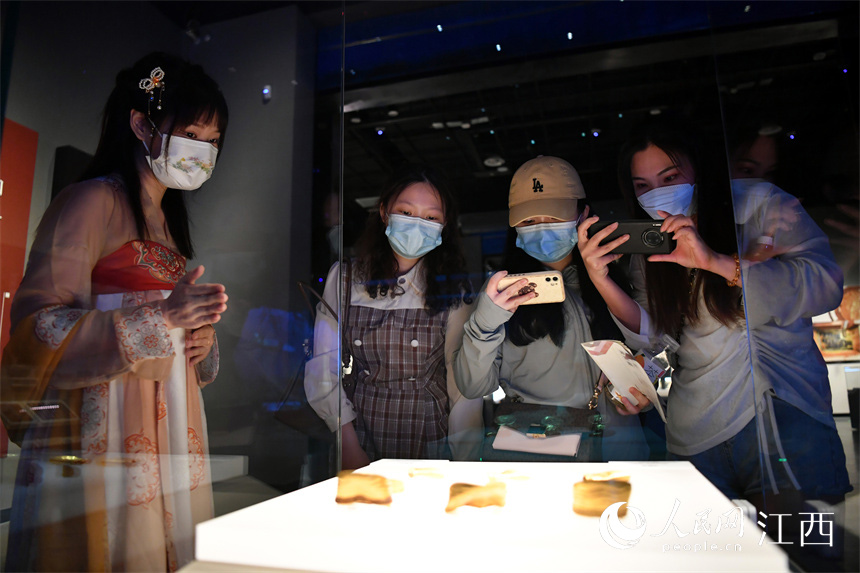 在江西省博物館內，市民正在參觀海昏侯墓出土的馬蹄金，身穿漢服的講解員正在講解。 人民網 時雨攝