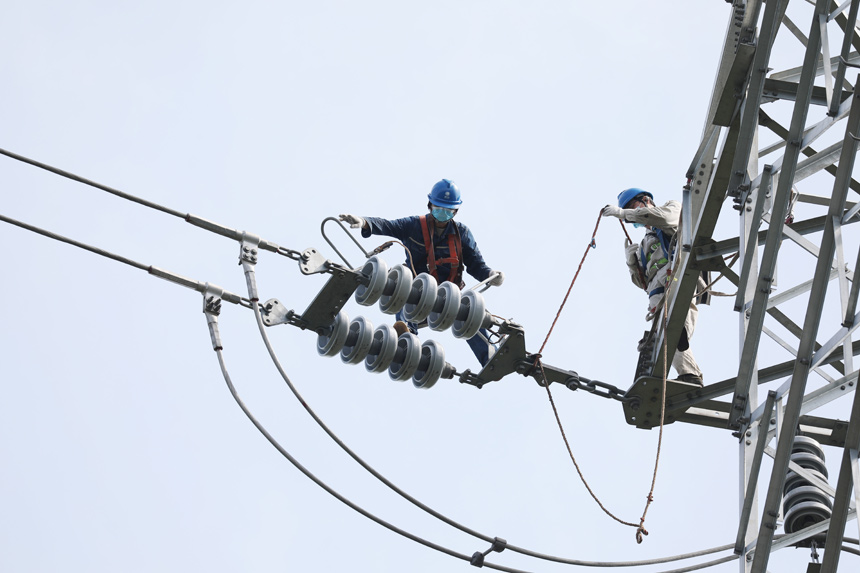 在江西省撫州市東鄉區楊橋殿鎮禮坊村境內一處高壓線塔上，電力施工隊員正在檢修電路。饒方其攝