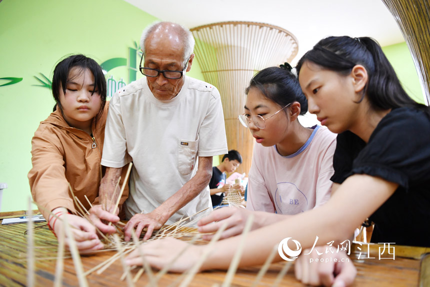 在蘆溪縣張佳坊學校，民間手藝人張友新正在教學生們竹篾編織。 人民網 時雨攝