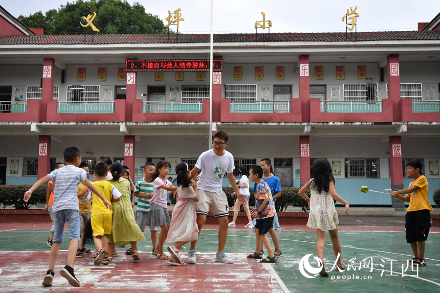 在学校操场上，支教学生和留守儿童们一起做游戏。 人民网 时雨摄