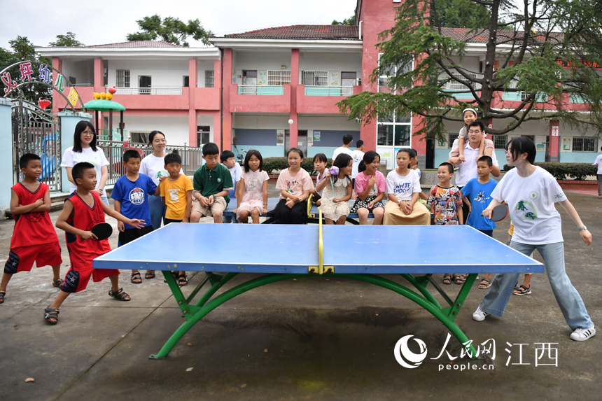 支教学生和留守儿童们在简易球桌上一起打乒乓球。 人民网 时雨摄