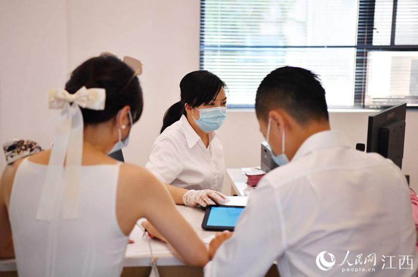 登記處工作人員正在為一對新人辦理結婚手續。 人民網 時雨攝