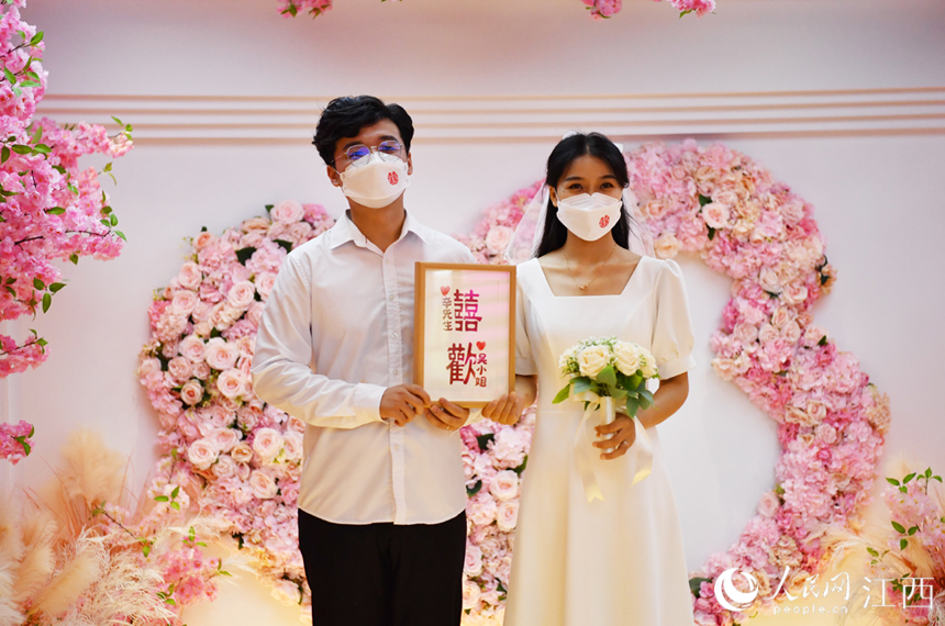 在登記處的玫瑰花牆前，一對新人展示愛的信物。 人民網 時雨攝