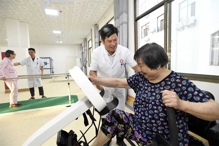 在宜豐縣流源社區仁愛康正醫養結合養老中心，老人在醫護人員的陪伴下進行康復訓練。周亮攝