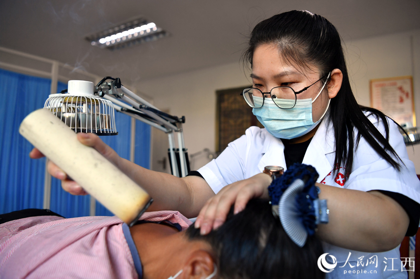 在樟树市永泰镇卫生院中医馆内，中医师正通过艾灸为村民治病。 人民网 时雨摄