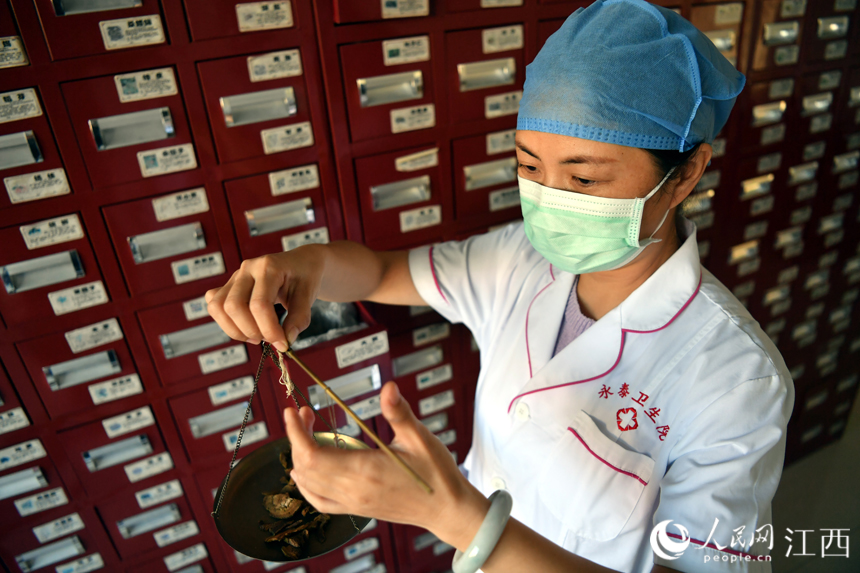 在樟树市永泰镇卫生院中医馆内，中药师正在抓药。 人民网 时雨摄
