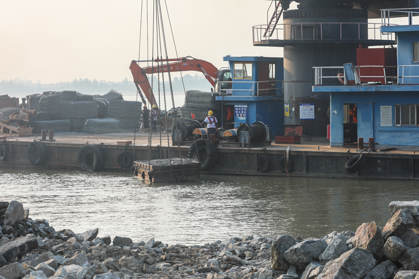 长江干流江西段崩岸应急治理工程江西九江城防堤段项目现场，作业人员正在施工船上开展水下护脚（抛石固脚）工程作业。刘力鑫 摄