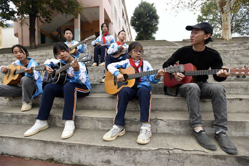樟樹市昌傅鎮中心小學的學生在音樂老師的指導下學彈吉他。周亮攝