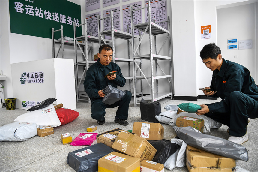 樟树市吴城乡客货邮综合服务中心，快递员在分拣包裹、录入信息。周亮摄