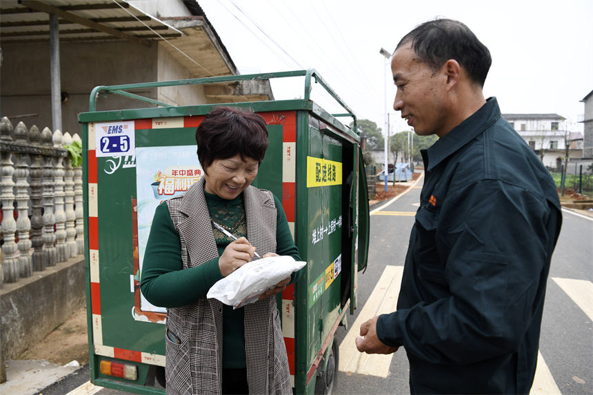 快递员将包裹送至塘下村村民手中。周亮摄