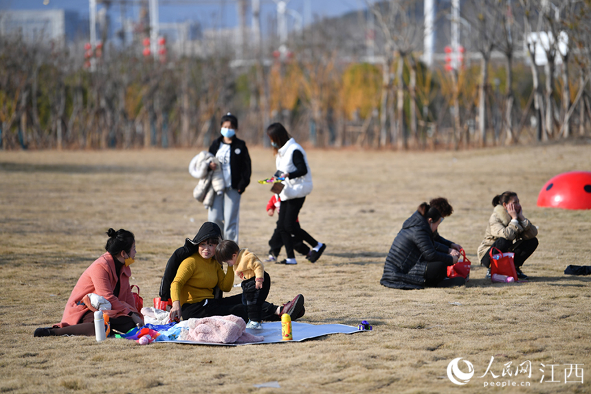 冬日午后，市民在公園內的草坪上晒太陽。 人民網 時雨攝