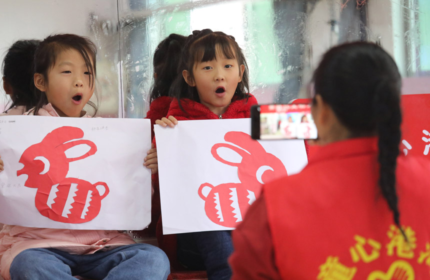 1月13日，在江西省抚州市乐安县惠民家园小区内，大学生自愿者给留守儿童拍照。邱志超摄