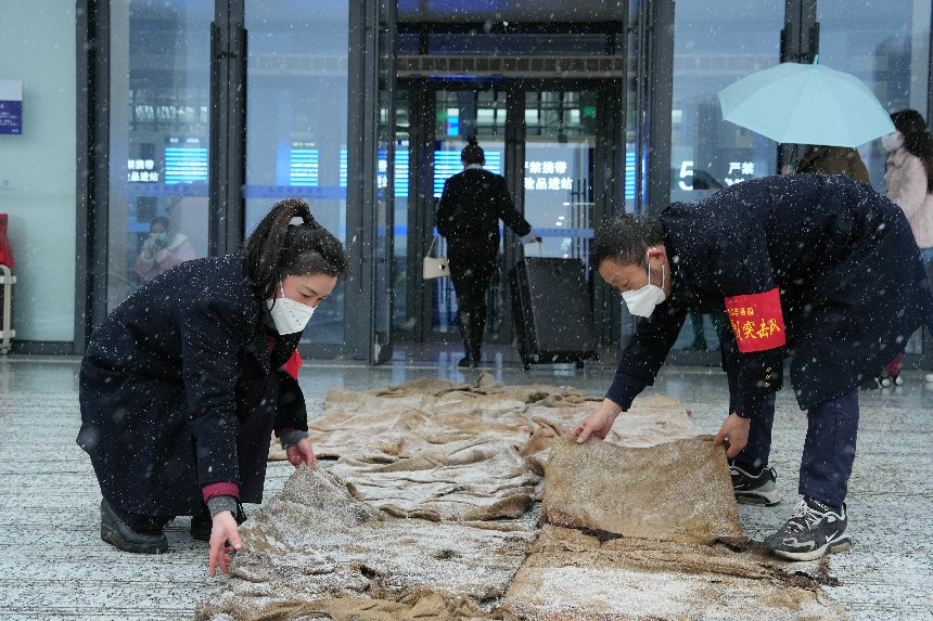 九江站工作人员在车站进站口位置铺设防滑草垫。 代建力摄