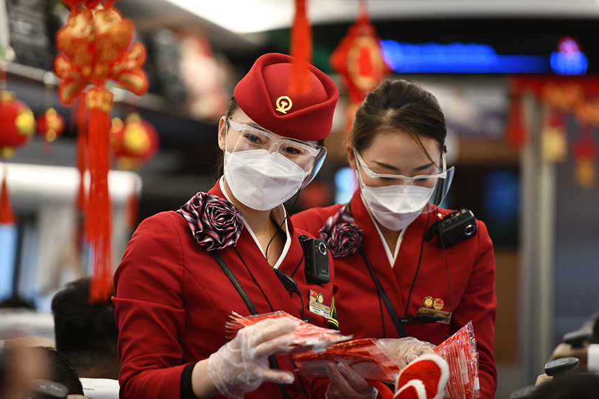 值乘G894列车的工作人员们正在与旅客互动，发放红色的口罩。郭钰祺摄