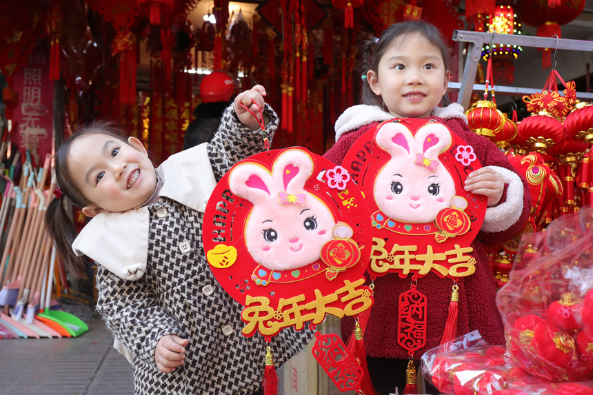 江西省宜豐縣黃墾鎮小朋友開心展示新購的兔年飾品。何賤來攝