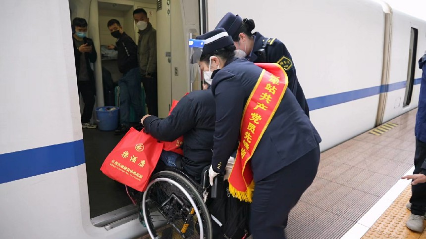 “红土情”服务台党员职工护送重点旅客上车。刘慕摄